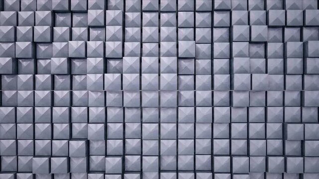 A close-up view of a wall composed of gray, geometric square tiles with pyramid faces