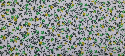 Close-up floral fabric pattern with small green and yellow flowers. Ideal for backgrounds, textures, textile design, and decorative projects.