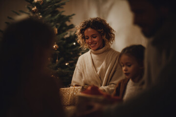 happy family gathered around beautifully decorated christmas tree joyfully opening presents by fireplace