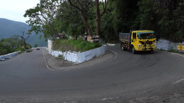 Yellow Eicher Truck driving downhill, A hairpin turn, Kolli Hills hairpin bends, Tamilnadu, India, Truck on road.