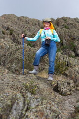 Portrait of a beautiful mature female tourist walking along the rocks in the Ural Mountains on a summer day