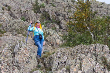 Portrait of a beautiful mature female tourist walking along the rocks in the Ural Mountains on a summer day