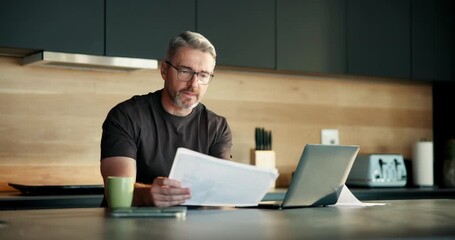 Reading, paperwork and man with laptop in kitchen, financial analysis or tax preparation with report. Review, documents and mature person with tech for asset management and self employed in home - Powered by Adobe