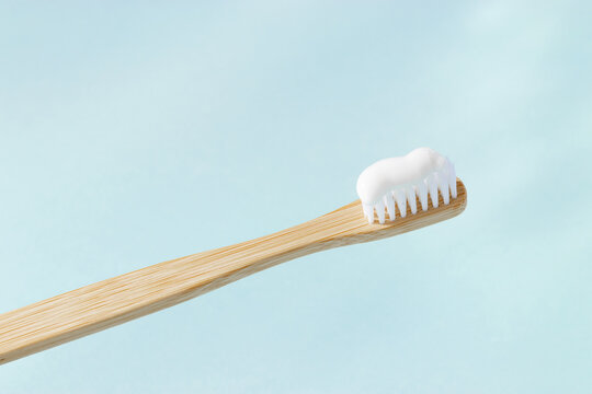 Close up Eco-friendly wooden bamboo toothbrush with white bristle and toothpaste for cleaning teeth on pastel blue background. Sustainable hygiene concept, zero waste lifestyle, eco conscious living - Powered by Adobe