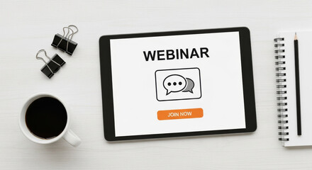 Webinar concept featuring a digital tablet on a white table surrounded by office supplies, black coffee, and a notebook. The tablet screen displays the text webinar and a speech bubble icon.
