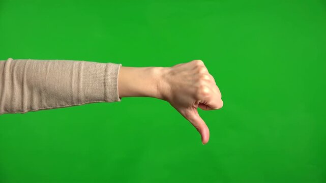 Hand gesture thumb down indicating disapproval or rejection on a green screen background