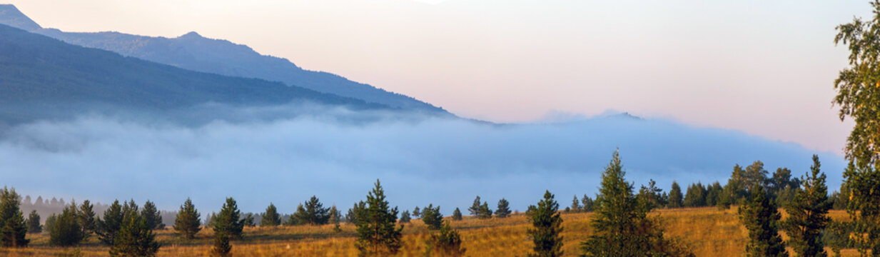 picturesque fog in the valleys of the Ural Mountains on a summer morning. Lake Talcas