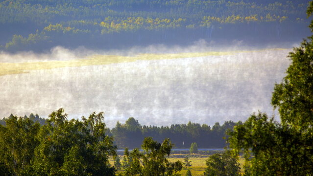 picturesque fog in the valleys of the Ural Mountains on a summer morning. Lake Talcas