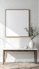 Empty picture frame on a white wall above a console table with a vase and plant bathed in natural sunlight.