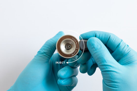 Gloved hands operating a manual HPLC valve, turning the handle to the Inject position for chemical analysis.