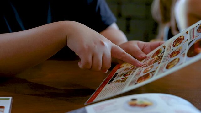 Customer Pointing at Menu While Choosing Food in Restaurant