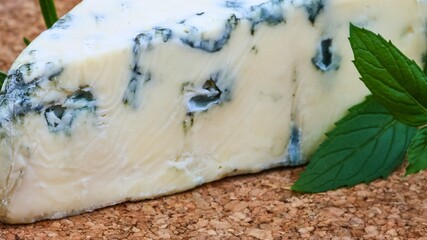Close up of a wedge of blue cheese with fresh mint leaves