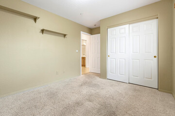 There is an empty bedroom that features a carpeted floor and a closet