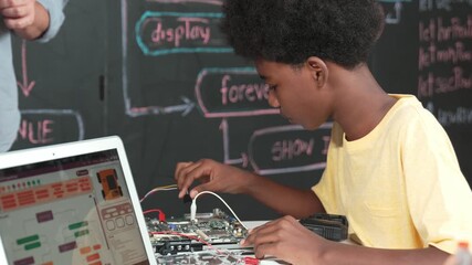 Cute african boy learning to use electronic tool while laptop display code while teacher talking about writing engineering prompt. Diverse children coding program to fixing car model. Edification - Powered by Adobe