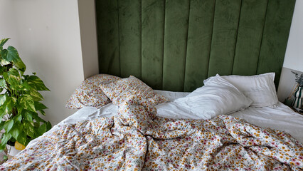 Cozy bedroom with rumpled sheets and green headboard