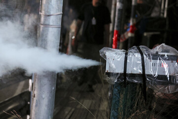 White smoke or fog effect from machine creating mysterious vapor. thick plume of artificial mist spray from metal pipe for cinematic special effect