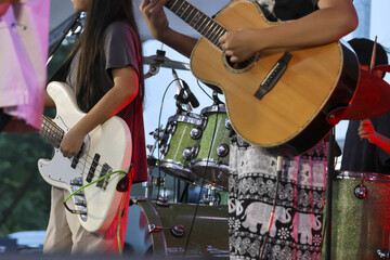 Music band with musician playing an acoustic guitar and electric bass during live concert performance on stage. Energetic musicians play their instruments with passion