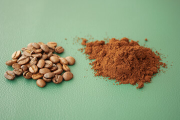 Coffee beans and ground coffee on green surface