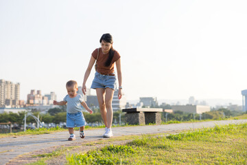 Fototapeta premium Mother and baby walking together in green park