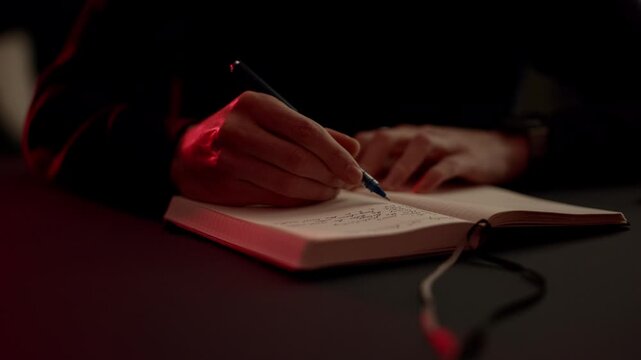 A person writing, journaling in a notebook with a pen, creating a calm journaling moment. Cozy warm light and cinematic tones highlight personal reflection and slow living.