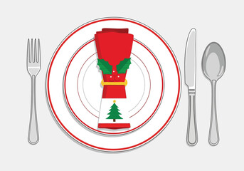 Christmas dinner place setting with a red napkin, holly, tree, fork, knife, spoon, and plate.