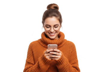 A young woman with her hair in a bun wearing glasses and an orange sweater smiles while looking at her smartphone isolated on transparent background