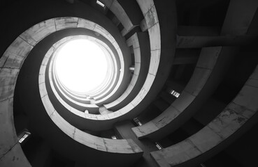 Fototapeta premium Low angle view shows inside spiral building. White circle opening at top. Black, white picture presents modern architecture with lines, curves abstract design pattern. Geometric style. Building
