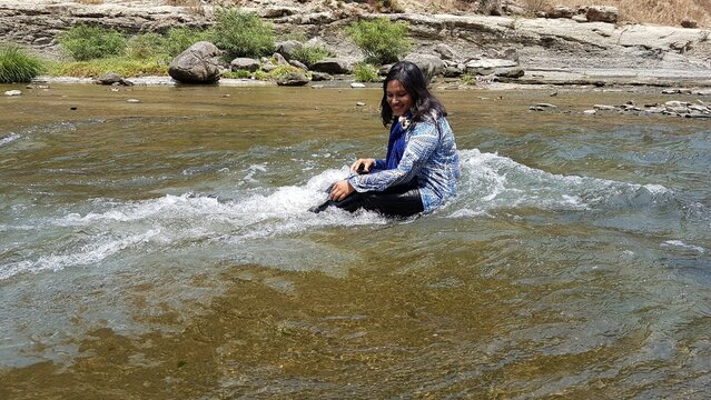Woman enjoying water activities in a river during the day. Sunny weather outdoors, smiling and happy