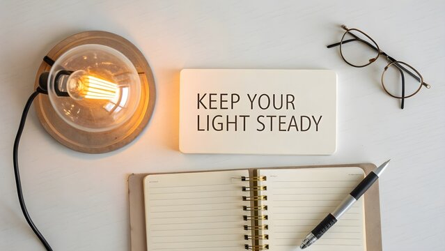 A glowing lamp with open journal and Keep Your Light Steady quote - Powered by Adobe