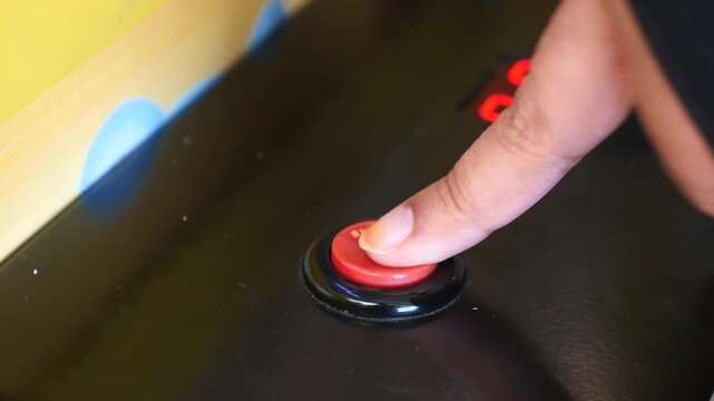 Finger pressing a button on a gaming machine in an arcade