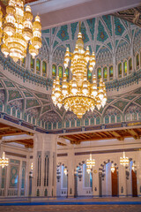 A stunning interior view of an Islamic mosque featuring grand golden chandeliers, an intricately patterned turquoise dome, and detailed Middle Eastern architectural elements