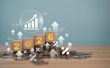 A wooden block with the year 2026 on top of a stack of coins represents investment strategies, financial planning, income goals, growth, action and success for the new year.