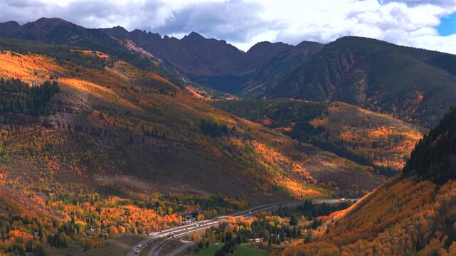 Vail Pass cars traffic i70 interstate highway Vail Colorado Rocky Mountains Gore Range drone aerial fall autumn season colorful quaking aspen trees morning blue skies sunny clouds forward pan up