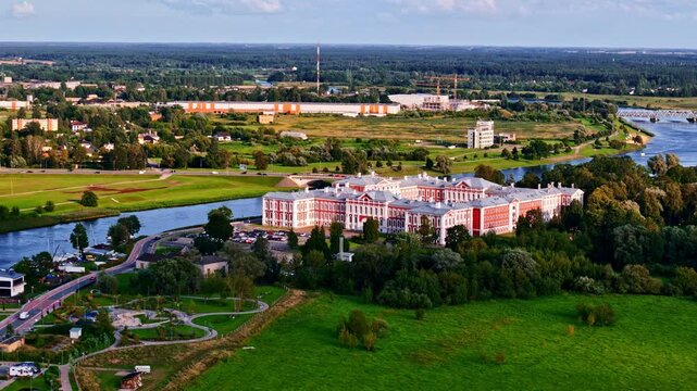 Jelgava Baroque style Palace on side of Lielupe river, aerial view with golden hour sunlinght
