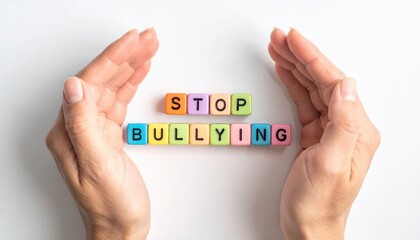 Hands forming a protective curve around colorful blocks spelling stop bullying on a bright white background creating a clear message of safety care and gentle support