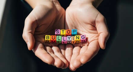 Open hands holding colorful letter blocks that spell stop bullying with strong sunlight creating sharp shadows and a focused scene that highlights protection care and a clear message of support