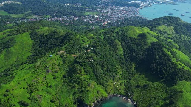 Bird&rsquo;s‑eye aerial of Nagbayog View Deck in Mariveles, Bataan, capturing lush green hills, winding paths, and the dramatic coastline meeting the calm turquoise sea below.