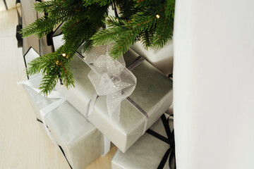Pine branches and elegant wrapped gifts on a light floor creating a festive scene.