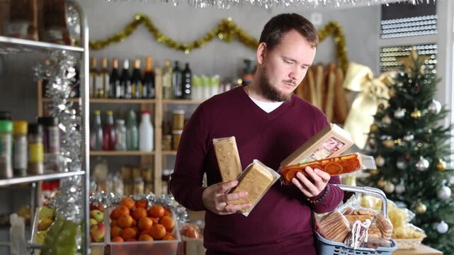 In festive little store decorated with Christmas tree and shiny tinsel, smiling young man with beard browsing shelves, picking out rich nutty turron and imagining joy of indulging in sweet delight