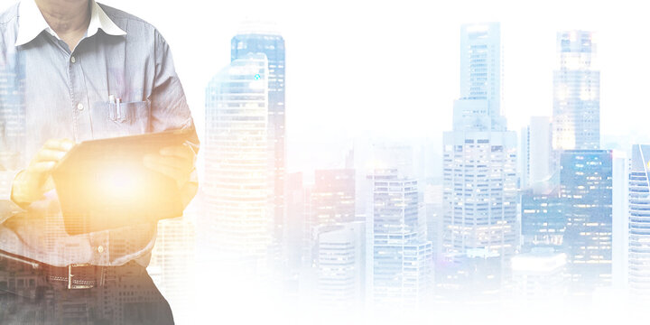 A manager working on tablet with glowing bright light on panoramic urban buildings blurry background. Image use for communication and technology industry presentation background.
