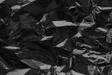 Shiny black foil texture background, pattern of wrapping paper with crumpled and wavy.