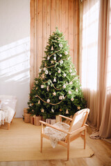 Decorated pine tree with presents beside wooden chair in cozy room interior with soft light.