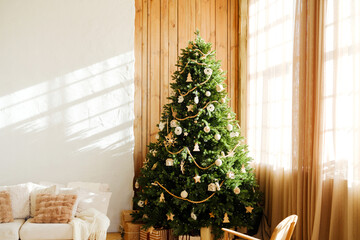 Decorated evergreen tree with ornaments and string lights indoors with sunlight streaming through