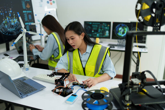 A female engineer is sitting and checking the operation of solar panels and wind turbines in the office. - Powered by Adobe