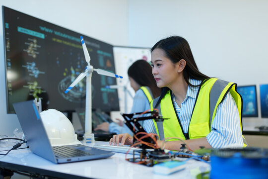 A female engineer is sitting and checking the operation of solar panels and wind turbines in the office.