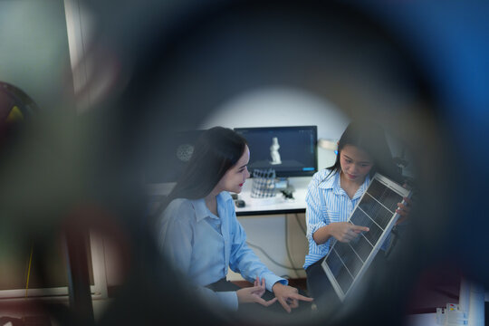 A female engineer is sitting and checking the operation of solar panels and wind turbines in the office.