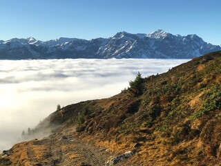 Late Autumn Landscape in the Engadin Swiss Alps with Golden Mountain Slopes, Morning Mist, Deep Blue Alpine Sky and snowcapped mountains 