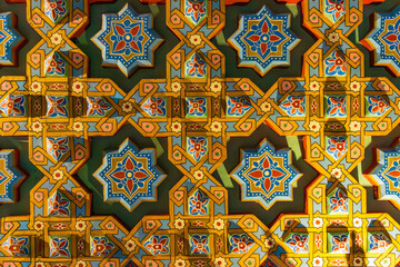 Traditional Moroccan geometric pattern with colorful carved shapes and decorative floral elements.