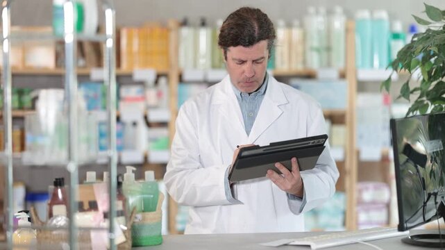 Man pharmacist makes restock, uses electronic carrier tablet of information. Checking availability of drugs, determining actual quantity of goods in warehouse.