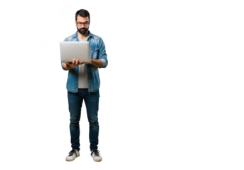Focused young man with beard wearing casual denim shirt and jeans holding a laptop computer isolated on transparent background